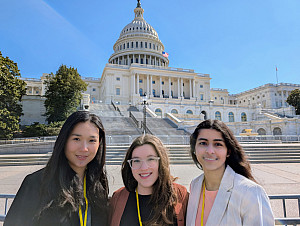 Three students pose in front of the Capitol building.